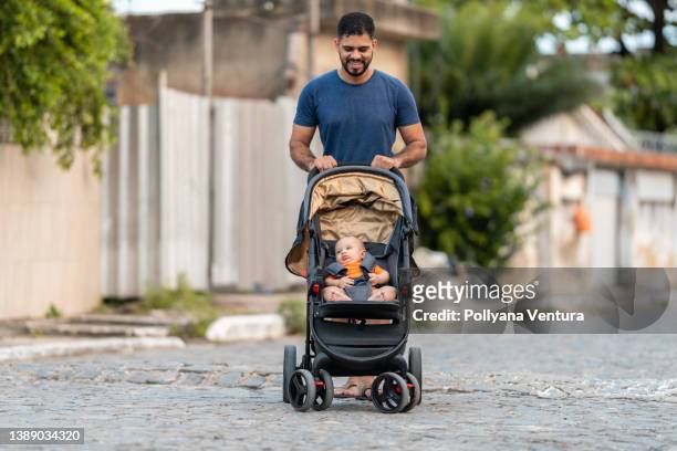 padre caminando con bebé en cochecito - cochecito de bebé fotografías e imágenes de stock