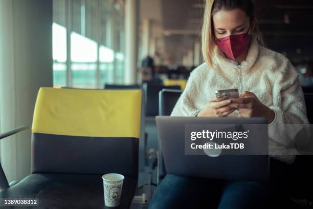 a female passenger waits for a flight at the airport, drinks coffee and uses a laptop and mobile phone. - lap body area stock pictures, royalty-free photos & images