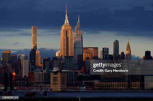 The sun sets on the skyline of midtown Manhattan, 432 Park Avenue, the Empire State Building, One Vanderbilt and the Chrysler Building in New York...