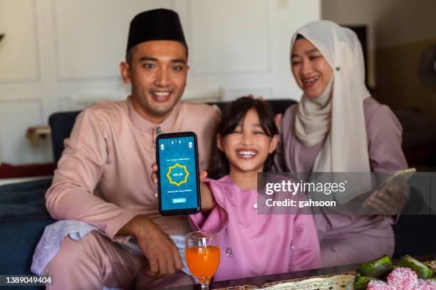 adolescente musulmana que recibe duit raya digital o sobre verde de sus padres durante hari raya aidilfitri - showing respect fotografías e imágenes de stock