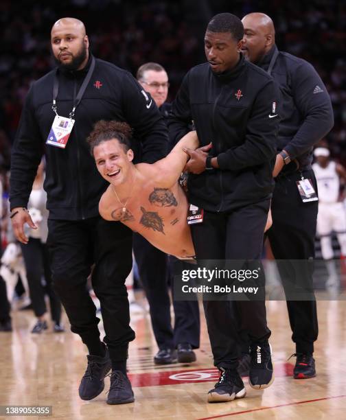 Houston Rockets team security tackles a spectator who ran onto the court and took his clothes off during the second half as the Sacramento Kings...