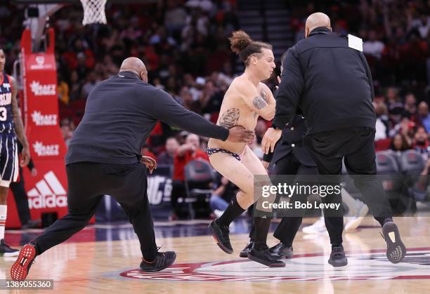 Houston Rockets team security tackles a spectator who ran onto the court and took his clothes off during the second half as the Sacramento Kings...
