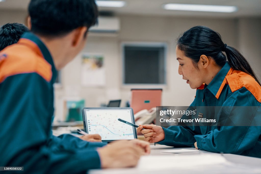 Three firefighters discussing a digital map on a tablet computer