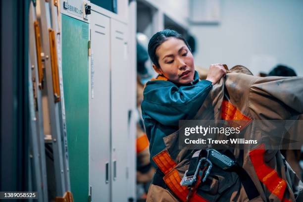 female firefighter putting on her protective equipment - 消防士　日本 ストックフォトと画像