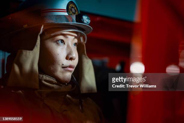 female firefighter looking confident while riding in a fire engine - 消防士　日本 ストックフォトと画像