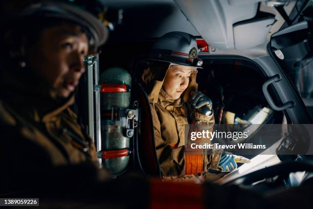 female firefighter reading a map and giving directions in a fire engine - emergency services fotografías e imágenes de stock