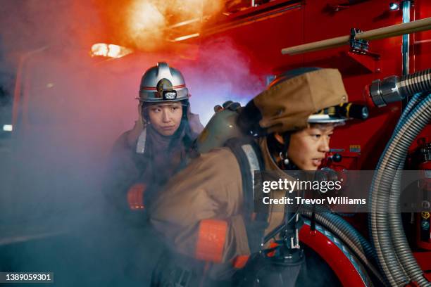 female firefighter helping a firefighter with an oxygen tank and mask - sacrifice stock pictures, royalty-free photos & images