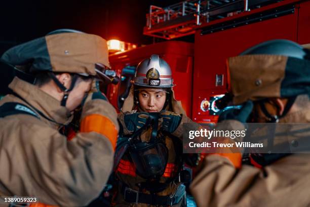 female firefighter putting on an oxygen mask next to a fire engine - fireman stock pictures, royalty-free photos & images