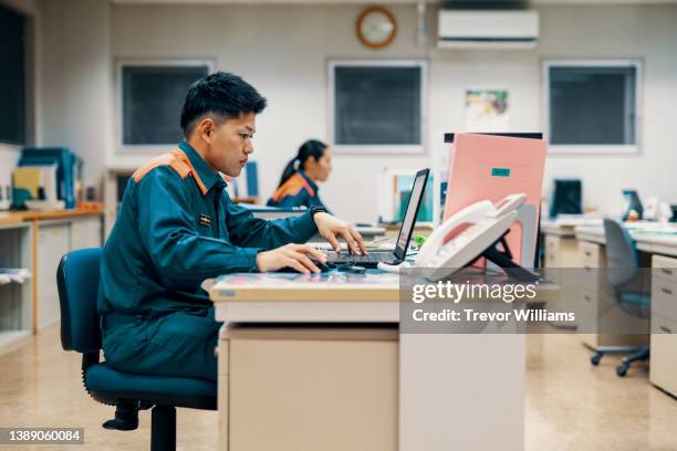 firefighter working on a computer in the fire department office - emergency planning ストックフォトと画像