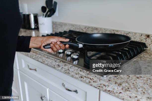 woman places frying pan on cooktop - gasbrander stockfoto's en -beelden