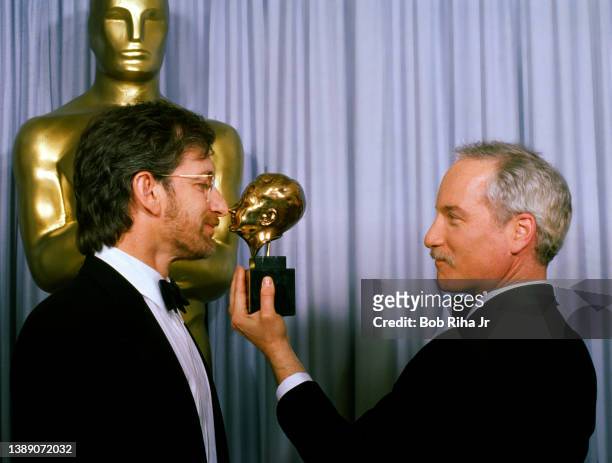 Richard Dreyfuss compares the side profile of Steven Spielberg with Spielbergs' Thalberg Award backstage at the Academy Awards Show, March 30, 1987...