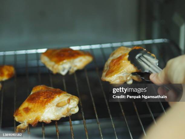 hand using tongs to hold grilled chicken in the oven, food animal - broiling stock pictures, royalty-free photos & images