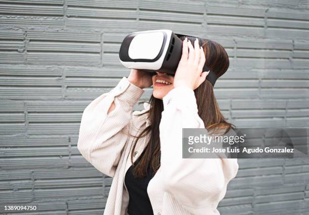 attractive girl wearing virtual reality headset outdoors, close up of woman using virtual reality headset outdoors, concept of person using augmented reality headset - viewfinder stockfoto's en -beelden