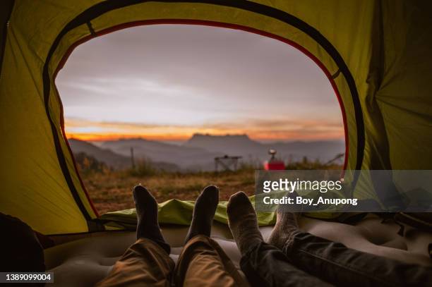 feet of two tourist lying in a tent and lookiing beautiful view of the chiang dao mountains from inside. - beautiful asian legs stockfoto's en -beelden