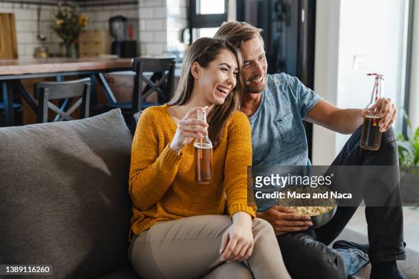 pareja joven relajándose en casa y viendo la televisión - estreno fotografías e imágenes de stock