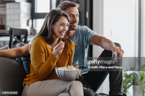 junges paar beim fernsehen im wohnzimmer - watching tv sofa stock-fotos und bilder