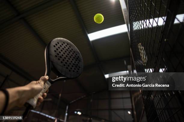 padel player hits ball in the air near the fence of the sports court - ball and hand in the air stockfoto's en -beelden