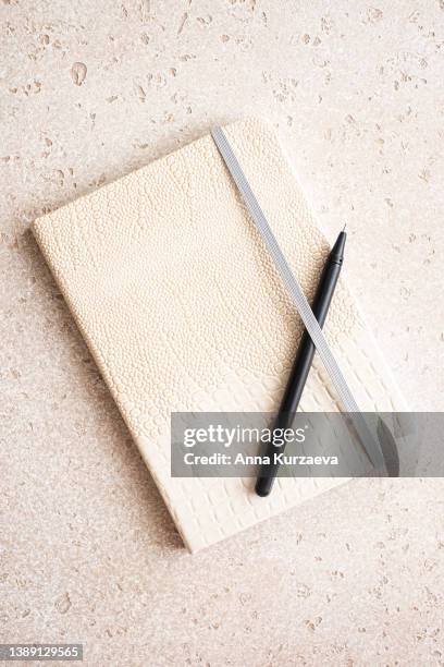 beige note pad with a black pen on concrete background, top view - schetsblok stockfoto's en -beelden