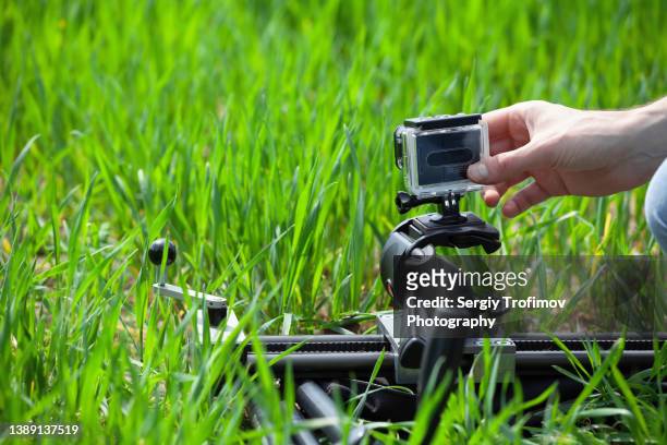 photographer in action taking a time lapse in green field - action camera stock pictures, royalty-free photos & images