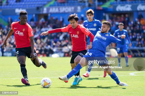 Take Kubo of RCD Mallorca is challenged by Oscar Rodriguez of Getafe CF during the LaLiga Santander match between Getafe CF and RCD Mallorca at...