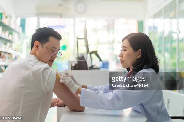 vaccines jabs, getting vaccination. doctor giving patient vaccination with feeling happy and relax. healthy and medical concept in local pharmacy. - pharmacist and patient imagens e fotografias de stock