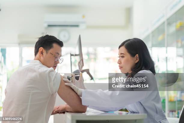 vaccines jabs, getting vaccination. doctor giving patient vaccination with feeling happy and relax. healthy and medical concept in local pharmacy. - pharmacy vaccination stock pictures, royalty-free photos & images