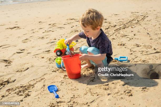 kleiner junge, der san castles am strand baut - kind sandburg stock-fotos und bilder