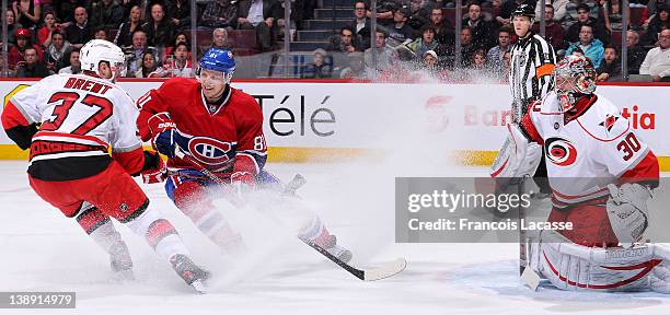 Lars Eller of the Montreal Canadiens battles for position with Tim Brent in front of goalie Cam Ward of the Carolina Hurricanes during the NHL game...