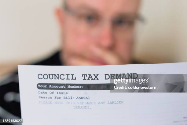 worried man checking council tax bill at home - government check stock pictures, royalty-free photos & images