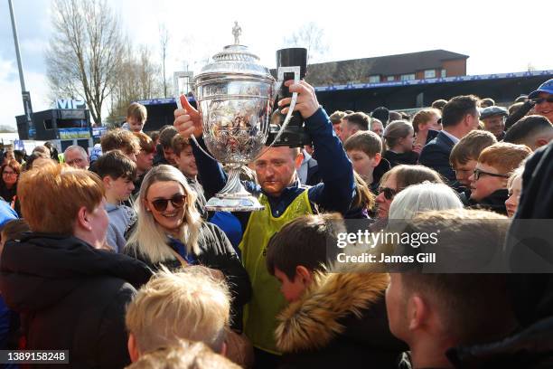 Member of the Macclesfield FC coaching staff takes the trophy through a crowd of supporters after the North West Counties Football League match...