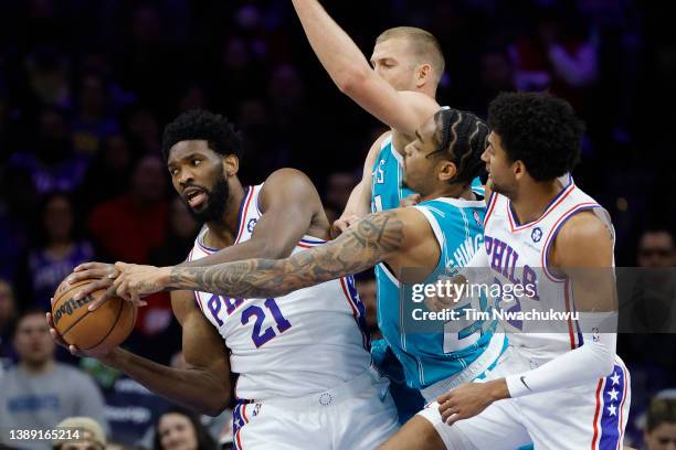 Joel Embiid of the Philadelphia 76ers gets a rebound as he's guarded by P.J. Washington and Mason Plumlee of the Charlotte Hornets during the first...