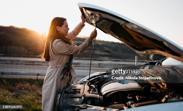 una mujer junto a un coche roto - avería de coche fotografías e imágenes de stock