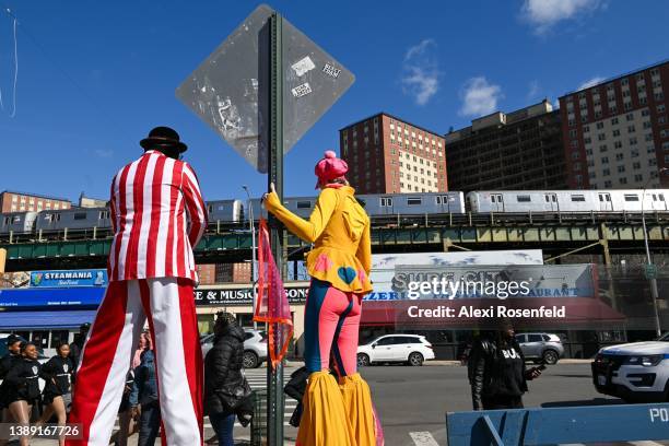 Performers on stilts lean on a street sign at Luna Park on the opening day of the season at Coney Island on April 2, 2022 in the Brooklyn Borough of...