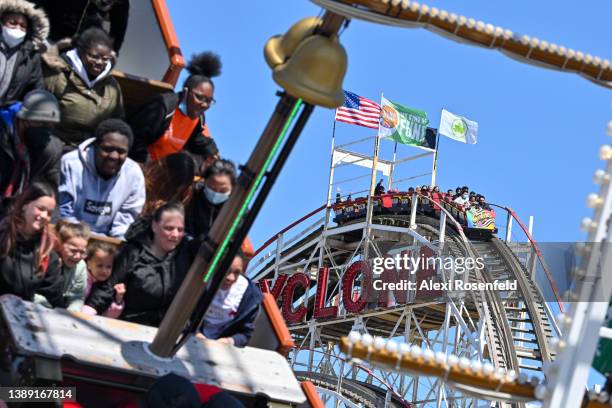 People riding the cyclone are framed by people riding the ship ride at Luna Park on the opening day of the season at Coney Island on April 2, 2022 in...