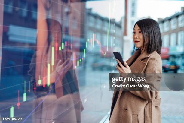 young asian businesswoman looking at stock exchange market trading board - etf fotografías e imágenes de stock