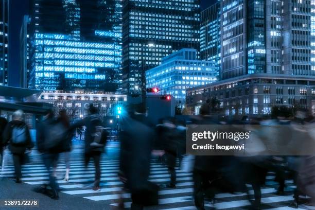 illuminated skyscrapers and business people in front of tokyo station - traffic light city stock-fotos und bilder