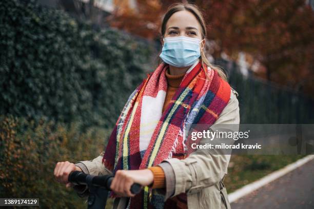 frau auf der straße mit einem roller - delta variante covid 19 stock-fotos und bilder