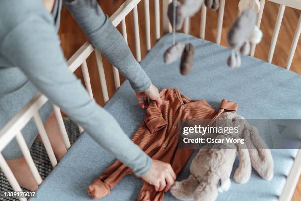 pregnant woman sorting out baby clothes and getting nursery ready - baby touching belly fotografías e imágenes de stock