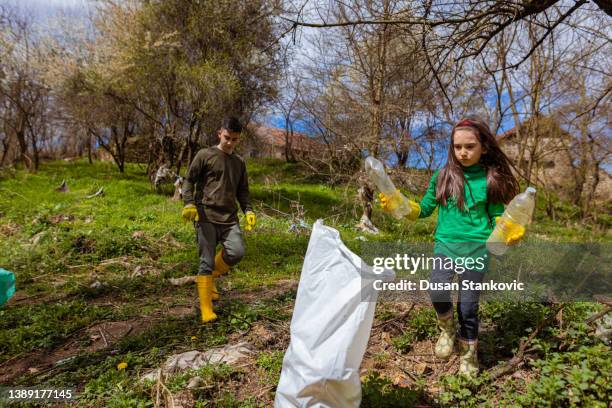 hermano y hermana recogiendo la basura en el bosque - contaminación de aguas fotografías e imágenes de stock