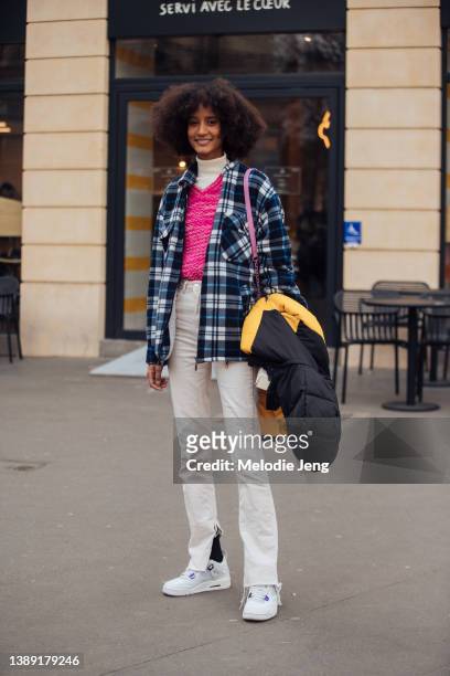 Allexia de Jesus wears a blue flannel jacket, pink sweater, white turtleneck, white mid-rise jeans, and white sneakers after The Row at during Paris...