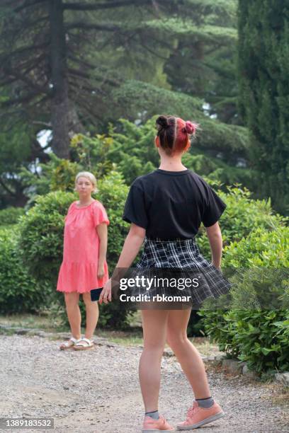 bizarre teenage daughter with pink hairstyle in short skirt leaving her mother in the park. conflict of parents and youth - girls with short skirts photos et images de collection