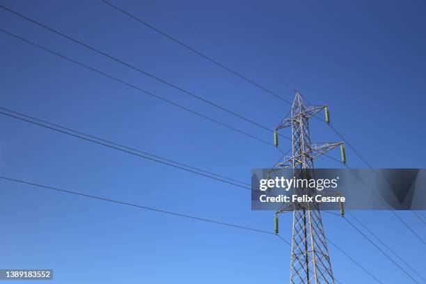 electricity pylon tower against a blue sky. electricity distribution. - corriente-de-alto-voltaje fotografías e imágenes de stock