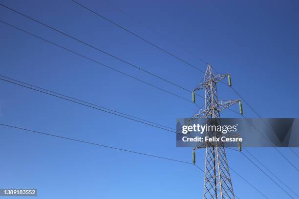 electricity pylon tower against a blue sky. electricity distribution. - power mast stock pictures, royalty-free photos & images