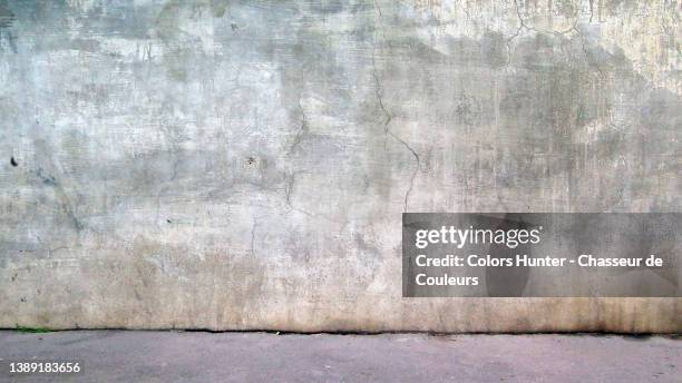 close-up of an empty cracked concrete wall with weathered paint and sidewalk in paris - building damage fotografías e imágenes de stock