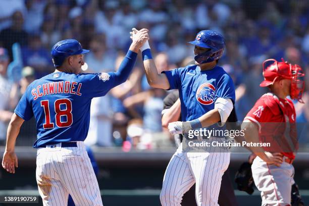 Seiya Suzuki of the Chicago Cubs high fives Frank Schwindel after hitting a two-run home run against the Los Angeles Angels during the fourth inning...