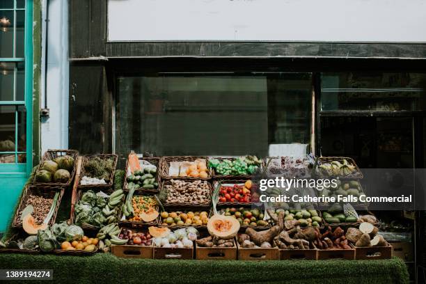 the exterior of a fruit and vegetable shop, with crates of fresh, raw produce displayed in front of the window. - gemüseladen stock-fotos und bilder
