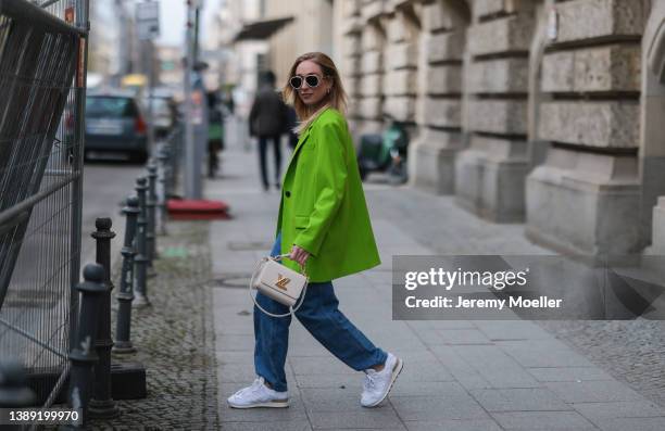 Sonia Lyson is seen wearing Miu Miu x New Balance white denim 574 sneaker, Boss blue denim jeans, Louis Vuitton mini twist leather beige bag, Versace...
