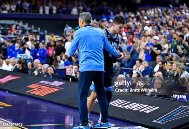 Collin Gillespie and head coach Jay Wright of the Villanova Wildcats embrace each other as they take on the Kansas Jayhawks during the second half in...