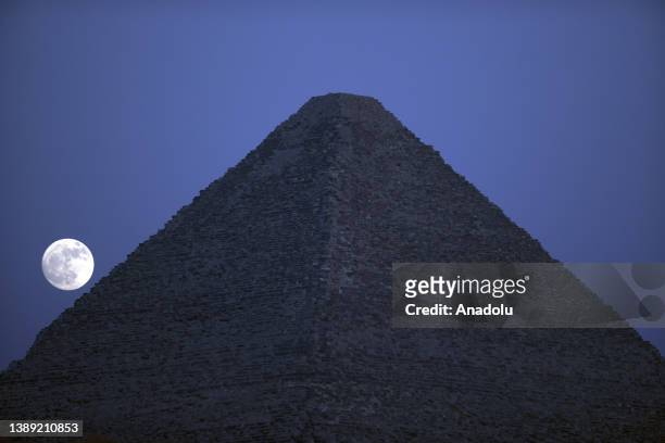 View of the Full Moon behind the Pyramids of Giza in Egypt on July 02, 2023.