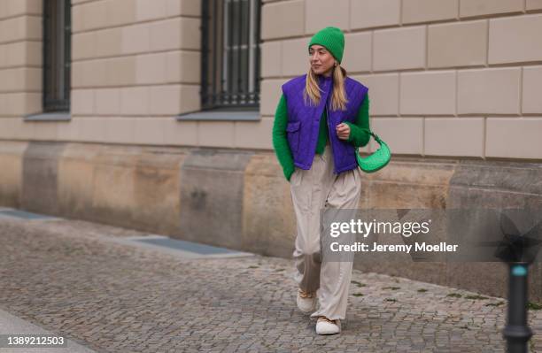 Sonia Lyson is seen wearing Nakd beige fluffy gold detail loafer, The Frankie Shop beige wide pants, The Frankie Shop lilac puffer vest, By Far Mini...